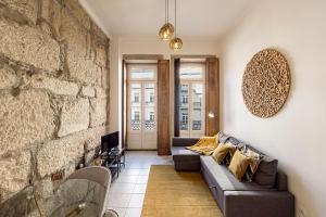 a living room with a couch and a stone wall at Wine Apartments in Porto