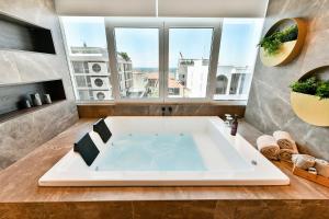 a large bath tub in a bathroom with a window at Porto Sea View Apartments in Thessaloniki