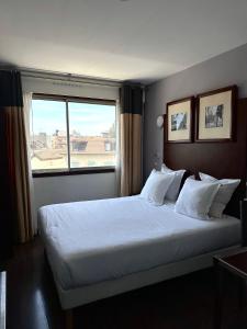 a bedroom with a large white bed with a window at Hôtel Du Centre Annemasse in Annemasse