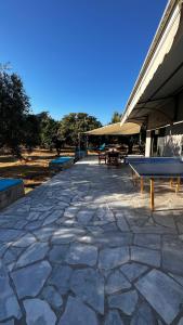 un patio con mesa de ping pong y bancos en Elaiocampus luxury house, en Kamáres