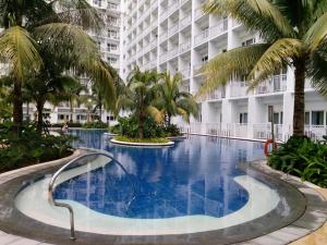 a large swimming pool with palm trees in front of a building at Mi Casa in Manila
