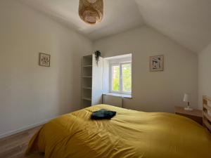 Un dormitorio con una cama amarilla y una ventana en La Cour de Clemenceau en Montbéliard