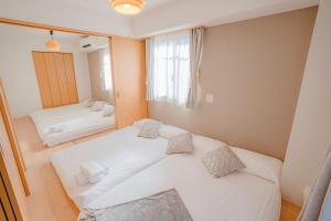 Schlafzimmer mit einem weißen Bett und einem Spiegel in der Unterkunft 桜の川7 Asakusa 901 Kuramae train 3mins Free WiFi Eight people quiet,cook,perfect facilities in Tokio