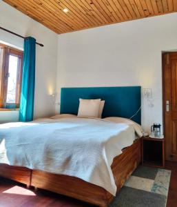 een slaapkamer met een groot bed met een blauw hoofdeinde bij Dolina Retreat in Mussoorie
