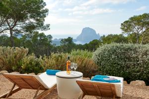 a table with a glass of wine and two chairs at Villa Ses Abelles in San Jose