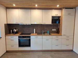 uma cozinha com armários brancos e um lavatório em Rovina Apartments em Gaschurn