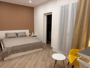 a bedroom with a bed and a yellow chair at Casa AnnaBella in Trapani