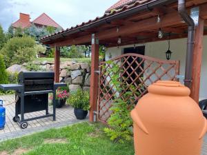 an outdoor grill with a wooden pergola and a grill at Biały Domek, noclegi Gołdap in Gołdap