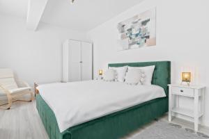 a bedroom with a large white bed with a green headboard at Park View in Oradea