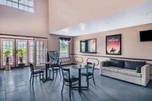 a living room with a couch and tables and chairs at Baymont by Wyndham Commerce GA Near Tanger Outlets Mall in Commerce