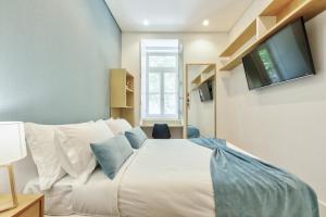 1 dormitorio con 1 cama blanca y TV en la pared en Avenue Garden, en Coímbra