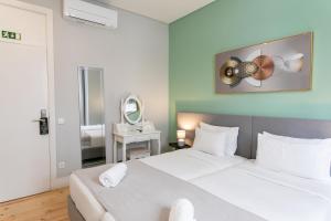 a bedroom with a large white bed and a mirror at Lisboa 85 Suites & Apartments by RIDAN Hotels in Lisbon