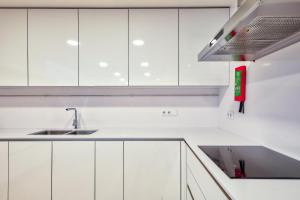 a white kitchen with white cabinets and a sink at Avenue Garden in Coimbra