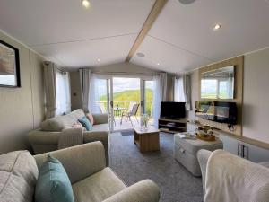 a living room with a couch and a tv and a table at Pass the Keys Gorgeous Kippford Home With Outstanding Views in Kippford