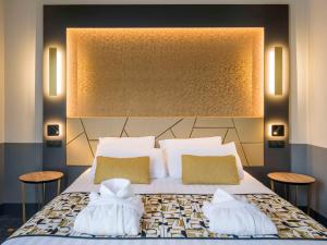 a bedroom with a large bed with two pillows at Hôtel Mercure Rodez Cathédrale in Rodez