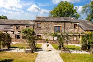 an old stone house with a garden in front of it at Threshing Barn at East Trenean Farm -Stunning Cornish Cottage sleeping 6 with hot tub, private garden, rural views and EV facilities in East Looe