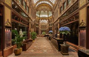a large building with a ceiling and a hallway with plants at Párisi Udvar Hotel Budapest, part of Hyatt in Budapest