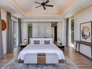 Premier Village Phu Quoc Resort Managed by Accor في فو كووك: غرفة نوم بسرير كبير مع مروحة سقف