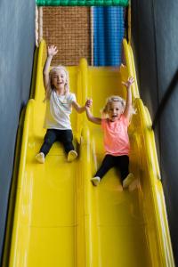 two little girls sliding down a yellow slide at Momentum Hotel in Anif