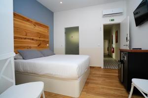 um quarto com uma cama branca e uma cabeceira em madeira em Alameda Guesthouse by Boutique Taipas Garagem para motos em Portimão
