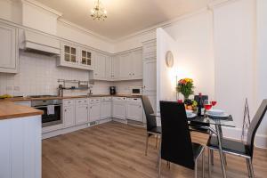 a kitchen with white cabinets and a table with chairs at Stay Thames River in London