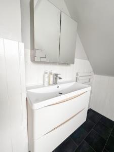 ein weißes Badezimmer mit einem Waschbecken und einem Spiegel in der Unterkunft The Reading Gem in Reading