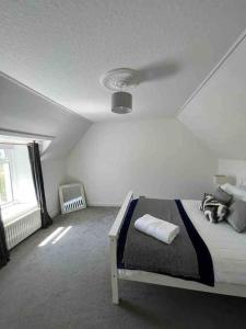 een witte slaapkamer met een bed en een raam bij Isla’s Cottage in Stornoway