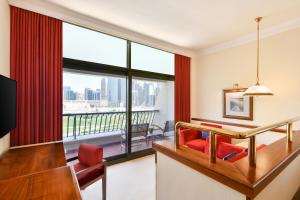 a hotel room with a desk and a large window at Sheraton Grand Doha Resort & Convention Hotel in Doha