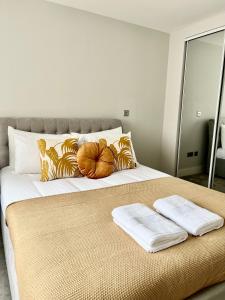 a bed with two towels and pumpkins on it at Deluxe 2 Bed 2 Bath Flat - Windsor, Heathrow Airport, Slough Station in Slough
