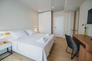 a white bed in a room with a desk and a chair at Ritsa Resort in Ureki