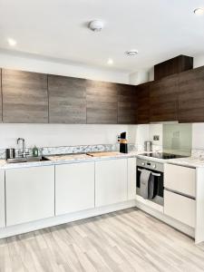a kitchen with white cabinets and wooden walls at Deluxe 2 Bed 2 Bath Flat - Windsor, Heathrow Airport, Slough Station in Slough