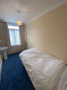 a bedroom with a white bed and a window at Victoria Guest House in Stoke on Trent