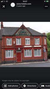 un edificio de ladrillo rojo con una puerta roja en una calle en Victoria Guest House, en Stoke on Trent
