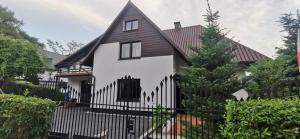 una casa blanca con una valla negra en Różana 4, en Nałęczów