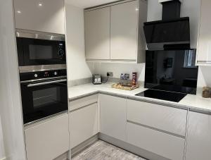 uma cozinha com armários brancos e um forno com placa de fogão em Regency Apartment em Hemel Hempstead