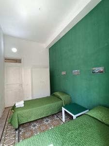 2 łóżka w pokoju z zielonymi ścianami w obiekcie La Melagrana w mieście Castellammare del Golfo