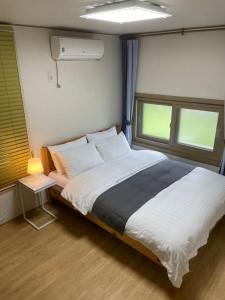 1 dormitorio con 1 cama grande y 2 ventanas en Onsaemiro, en Seogwipo