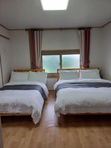 - 2 lits dans une chambre avec fenêtre dans l'établissement Onsaemiro, à Seogwipo