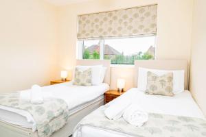 2 camas individuales en una habitación con ventana en Free Parking Good Location Lavender Harmony House, en Swindon
