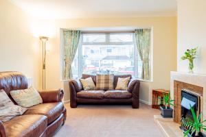 a living room with a leather couch and a fireplace at Free Parking Good Location Lavender Harmony House in Swindon