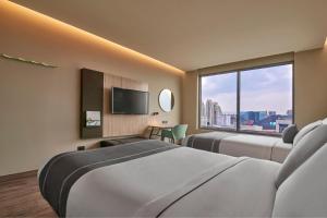 a hotel room with two beds and a large window at City Express Plus by Marriott Interlomas in Mexico City