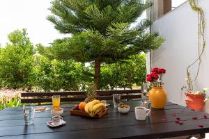 a wooden table with fruit and drinks and a tree at The backyard- Κατοικία στην Αγριά, Βόλου in Agria