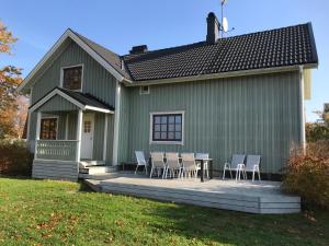 アルベスタにあるFridhem gröna hus 14 pers och Fridhem röda hus 8 persのデッキにテーブルと椅子を用意した緑の家