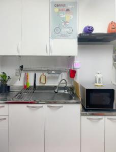 eine Küche mit weißen Schränken, einer Spüle und einer Mikrowelle in der Unterkunft ARMYCasa with 2 rooms and 1 bathroom in Seoul