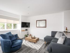 a living room with two blue chairs and a couch at 39 Alwen Drive in Rhos-on-Sea