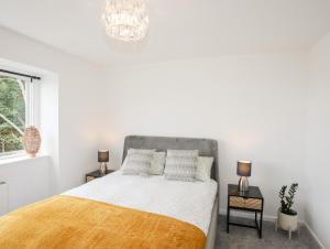 a white bedroom with a bed and a chandelier at 39 Alwen Drive in Rhôs-on-Sea