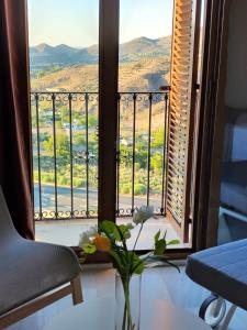 a vase with flowers on a table in front of a window at Balcón de la Villa in Priego de Córdoba