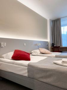 dwa łóżka z czerwoną poduszką na górze w obiekcie Ośrodek Magnolia w Ustroniu