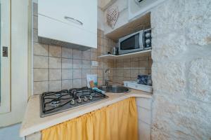 a kitchen with a stove and a sink and a microwave at Salentina by Rentbeat in Ostuni +11 photos