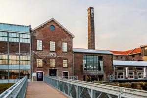 un viejo edificio de ladrillo con un puente delante de él en Modern Studio & Apartment Roermond en Roermond